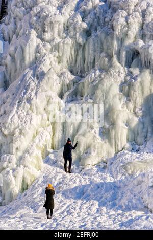 Zwei Frauen erkunden die Eisformationen an den gefrorenen Rutschen de Chaudière in Charny in der Nähe von Quebec City, Kanada Stockfoto