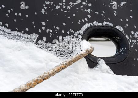 Eisiger Rumpf mit Verankerungsloch und Seilen an der Pier, Nahaufnahme Stockfoto