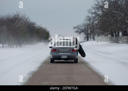 Flower Mound, Texas, USA. Februar 2021, 17th. 2/17/21 Flower Mound, Texas EIN Auto fährt eine einspurige schneegepflügte Straße mit einem Zwischenrohr aus ihrem Fahrzeug hängen. Texaner haben einen Weg gefunden, diesen Wintersturm in ein unterhaltsames Erlebnis zu verwandeln. Quelle: Chris Rusanowsky/ZUMA Wire/Alamy Live News Stockfoto