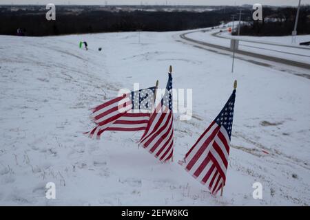 Flower Mound, Texas, USA. Februar 2021, 17th. 2/17/21, Flower Mound, Texas - drei amerikanische Flaggen stehen auf einem beliebten Rodelhügel. Texaner haben einen Weg gefunden, diesen Wintersturm in ein unterhaltsames Erlebnis zu verwandeln. Quelle: Chris Rusanowsky/ZUMA Wire/Alamy Live News Stockfoto