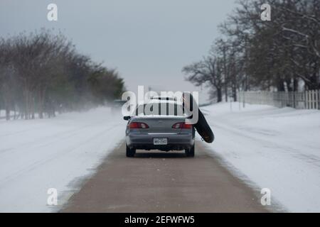 Flower Mound, Texas, USA. Februar 2021, 17th. Ein Auto fährt auf einer einspurigen, schneebedeckten Straße mit einem Zwischenrohr aus dem Fahrzeug. Texaner haben einen Weg gefunden, diesen Wintersturm in ein unterhaltsames Erlebnis zu verwandeln. Quelle: Chris Rusanowsky/ZUMA Wire/Alamy Live News Stockfoto