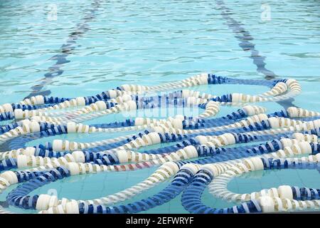 Ein einzigartiger Blick auf die blauen und weißen Seile am Ende eines Schwimmbades. Unter Wasser sichtbare Bahnlinien. Stockfoto