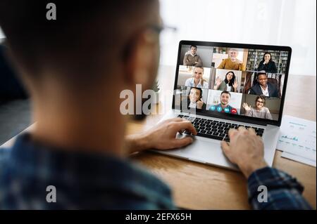 Über die Schulter zu einem Laptop-Bildschirm mit vielen multirassischen erfolgreichen Mitarbeitern, Kollegen kommunizieren per Videoanruf, Online-Meeting-Konzept. Videokonferenz mit vielen Menschen zusammen Stockfoto