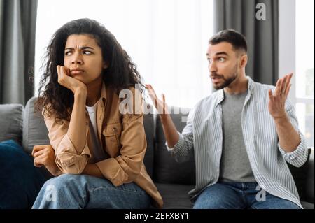 Verheiratete junge Paar emotionale diskutieren über etwas, sie haben Problem. afroamerikanische Frau und kaukasischer Mann sind sich nicht einig haben ein Missverständnis, kann nicht entscheiden, ein Streit Stockfoto