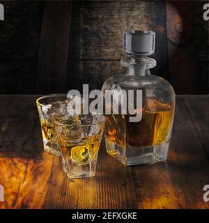 Eine Whiskey Flasche und zwei Gläser auf den Felsen Ein Holztisch Stockfoto