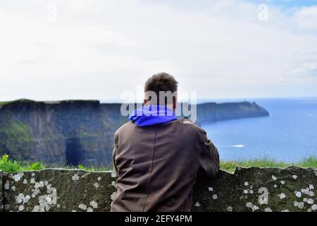 Liscannor, County Clare, Irland. Mann, der die raue Schönheit der Cliffs of Moher einnimmt. Stockfoto