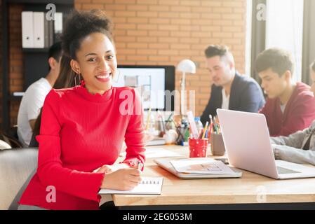 Legere afro-karibische Geschäftsfrau im Tagungsraum mit Inneneinrichtung Unternehmen mit interracial Kollegen Stockfoto