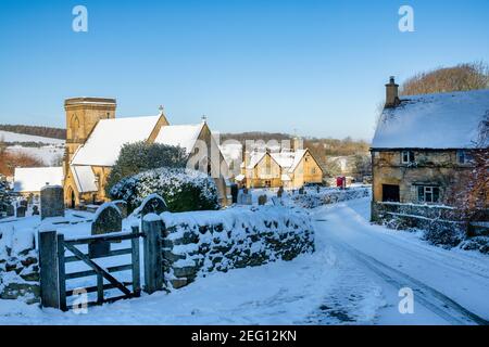 Cotswold Steinhütten und Kirche im Januar Schnee. Snowshill, Cotswolds, Gloucestershire, England Stockfoto