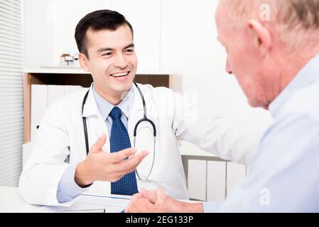 Lächelnder Arzt, der sich mit einem älteren männlichen Patienten besprache Stockfoto