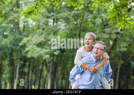 Ein älterer Mann, der seine Frau im Park trägt Stockfoto