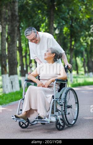 Der alte Mann schiebt seine Frau im Rollstuhl hinein Der Park Stockfoto