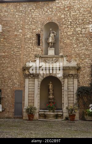 Alte Skulptur mit kleinem Brunnen und Pflanzen und Blumen in Töpfe Stockfoto