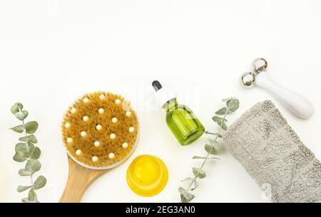 Gesichtsöl und Gesichtswalze, Bürste für trockene Massage und ein Baumwolltuch liegen auf einem Holztablett Stockfoto