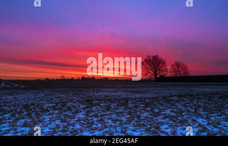 Spektakulärer Wintersonnenaufgang über flachem Ackerland Stockfoto