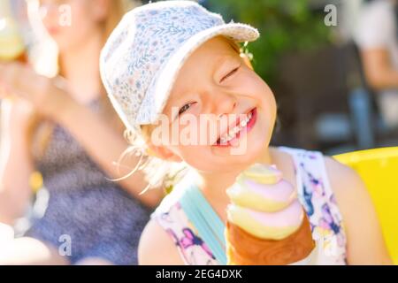 Portrait eines kleinen Mädchens, das lächelt und Eis hält In einem sonnigen Sommertag und Blick in ein Kamera Stockfoto