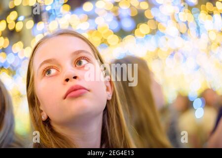 Portrait von blonden Haaren Teenager-Mädchen auf einem Hintergrund mit Lampen mit verschwommenem Licht Stockfoto