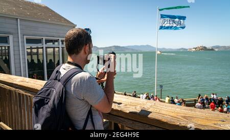San Francisco, Kalifornien, USA - August 2019: Mann, der Alcatraz Island fotografiert, steht im Pier 39 der Fischerhafen Stockfoto