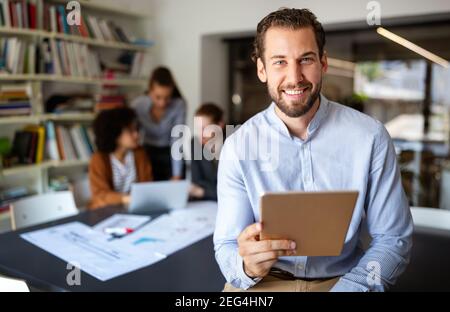 Porträt eines Geschäftsmannes mit Tablet im Büro und Kollegen diskutieren Im Hintergrund Stockfoto