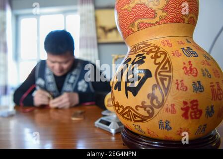 (210218) -- HORGOS, 18. Februar 2021 (Xinhua) -- Cao Guangyao arbeitet an pyrographischen Kalabash-Kunstwerken in seinem Atelier in Horgos, nordwestlich von Xinjiang Uygur Autonome Region, 6. Februar 2021. Cao Guangyao ist ein 45-jähriger Bauer in Horgos. Er ist auch bei den Einheimischen als Künstler für seine pyrographischen Kalabash-Kunstwerke bekannt. Als Maler-Enthusiast interessierte sich Cao vor 8 Jahren für pyrographische Kreation aus TV-Shows und begann seitdem seine eigene Kreation. Trotz keiner beruflichen Ausbildung, Cao machte Kunst Versuche immer wieder mit Liebe und Leidenschaft während der Lacksaison der Landwirtschaft Stockfoto