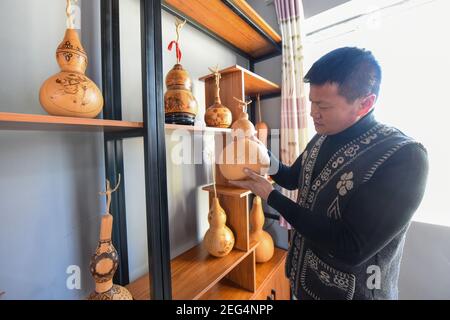 (210218) -- HORGOS, 18. Februar 2021 (Xinhua) -- Cao Guangyao bewertet pyrographische Kalabash-Kunstwerke in seinem Atelier in Horgos, im Nordwesten Chinas, Xinjiang Uygur Autonome Region, 6. Februar 2021. Cao Guangyao ist ein 45-jähriger Bauer in Horgos. Er ist auch bei den Einheimischen als Künstler für seine pyrographischen Kalabash-Kunstwerke bekannt. Als Maler-Enthusiast interessierte sich Cao vor 8 Jahren für pyrographische Kreation aus TV-Shows und begann seitdem seine eigene Kreation. Trotz keiner beruflichen Ausbildung, Cao machte Kunst Versuche immer wieder mit Liebe und Leidenschaft während der Lacksaison der Landwirtschaft Stockfoto