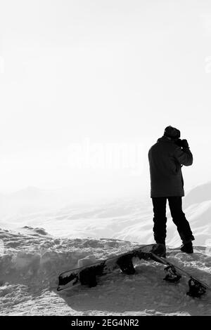 Skifahrer macht Foto mit der Kamera auf dem schneebedeckten Berg im Nebel. Kaukasus im Winter, Georgien, Region Gudauri. Schwarzweißbild. Hoch Stockfoto