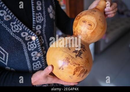 (210218) -- HORGOS, 18. Februar 2021 (Xinhua) -- Cao Guangyao zeigt ein pyrographisches Kalabash-Kunstwerk zum Thema Kampf gegen die COVID-19 Pandemie in Horgos, nordwestlich der Autonomen Region Xinjiang Uygur in China, 6. Februar 2021. Cao Guangyao ist ein 45-jähriger Bauer in Horgos. Er ist auch bei den Einheimischen als Künstler für seine pyrographischen Kalabash-Kunstwerke bekannt. Als Maler-Enthusiast interessierte sich Cao vor 8 Jahren für pyrographische Kreation aus TV-Shows und begann seitdem seine eigene Kreation. Trotz keiner professionellen Ausbildung, Cao machte Kunst Versuche immer wieder mit Liebe und Leidenschaft duri Stockfoto