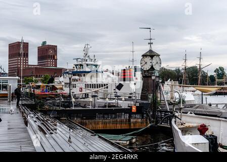 Oslo, Norwegen - 10. August 2019: Blick auf den Hafen von Aker Brygge mit Rathaus im Hintergrund Stockfoto