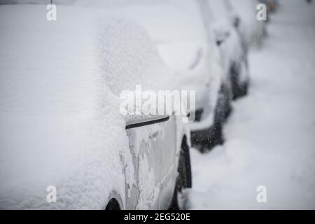 Geparkte Autos mit Schnee im Winter Schneesturm bedeckt Stockfoto