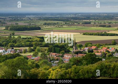 Landschaftlich schöner Blick auf das Dorf Bishop Wilton (Häuser und Kirche) & offene, flach liegende Felder im Tal von York - Yorkshire Wolds, East Riding, England Großbritannien. Stockfoto