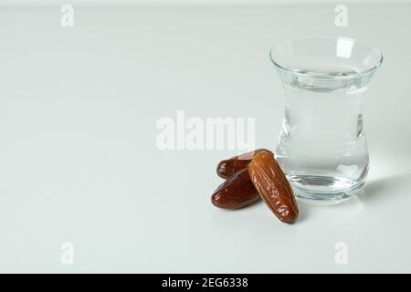 Glas Wasser und Datteln auf weißem Hintergrund Stockfoto