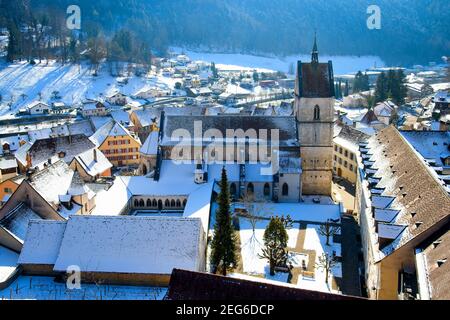 Erhöhter Blick auf die Stiftskirche Saint Ursanne und ihren Kreuzgang in der charmanten mittelalterlichen Stadt Saint Ursanne, Kanton Jura, Schweiz. Stockfoto