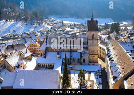 Erhöhter Blick auf die Stiftskirche Saint Ursanne und ihren Kreuzgang in der charmanten mittelalterlichen Stadt Saint Ursanne, Kanton Jura, Schweiz. Stockfoto