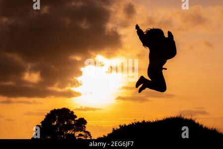 Silhouette der Frau springen glücklich, während des Sonnenuntergangs, Reiseziel Azoren, Sao Miguel Insel. Stockfoto