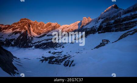 Sarradets Berghütte (auch Refuge de la Brèche de Roland genannt) und Blick auf den Cirque de Gavarnie (Gavarnie, Pyrenäen, Frankreich) bei Sonnenuntergang Stockfoto