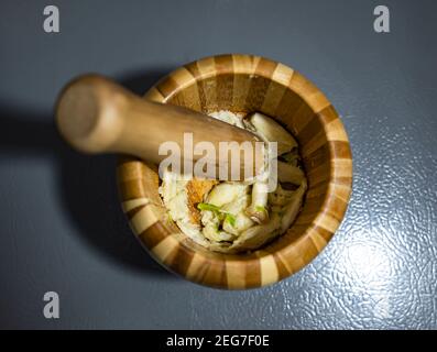 Ein Bild von Knoblauch, der zerstoßen wurde. In einem Mörser mit Stößel. Stockfoto