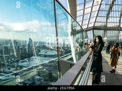 London, UK- 15 Dec 2020: Asiatische Touristen fotografieren die Skyline von London von der Sky Garden Terrasse aus. Junge Frau im schwarzen Mantel stehend Stockfoto