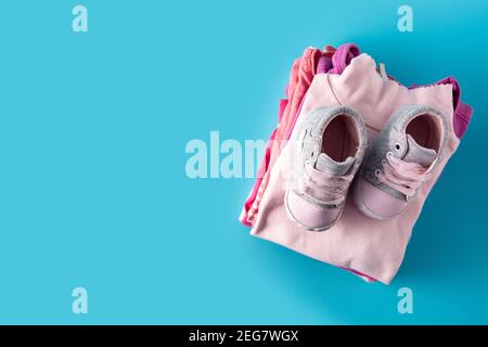 Baby Strampler und Babyschuhe auf blauem Hintergrund Stockfoto