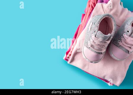 Baby Strampler und Babyschuhe auf blauem Hintergrund Stockfoto