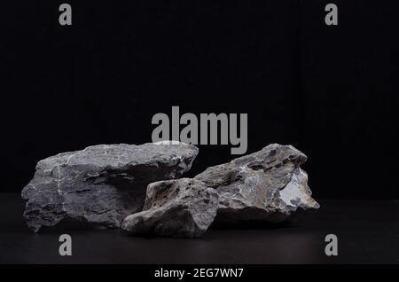 Graues Marmorstein Podium für Verpackung und kosmetische Präsentation auf schwarzem Hintergrund, Kopierraum. Natürlicher und starker Style. Stockfoto