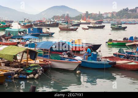 Cheung Chau Insel in der Nähe von Hong Kong, China. Der Hafen. Mann, der im Fischerboot sitzt, um Netze auszubessern. Stockfoto