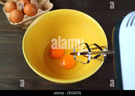 Nahaufnahme des elektrischen Eierbeaters, der APAIR schlägt Rohe Eier in Rührschüssel Stockfoto