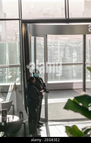 London, UK- 15 Dec 2020: Sicherheitskräfte auf der Sky Garden Terrasse bei der Arbeit mit Masken und Handschuhen, Mann und Frau stehen in Uniformen am Eingang zu Stockfoto