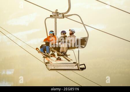 Eine Gruppe von Teenagers, die im warmen Abendlicht auf einem Sessellift reiten. Stockfoto