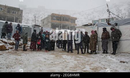 Libanon 2 18 2021: Flüchtlinge im Flüchtlingslager in E'rsal warten auf die Verteilung von Spenden an den syrischen libanesischen Grenzen im Winter Schneesturm Schneesturm Stockfoto