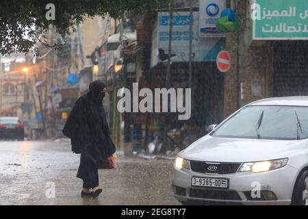 Gaza-Stadt, Palästina. Februar 2021, 18th. Eine Palästinenserin geht am 18. Februar 2021, als es in Gaza-Stadt regnet. (Foto von Mahmoud Khattab/INA Photo Agency/Sipa USA) Quelle: SIPA USA/Alamy Live News Stockfoto