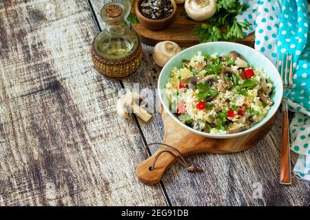 Diät Essen veganes Konzept. Veganer Salat mit Couscous und Champignons auf einem Holztisch. Speicherplatz kopieren. Stockfoto