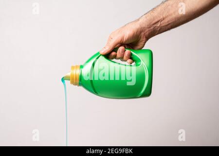 Gießen von Reinigungsflüssigkeit aus der grünen Flasche vor hellgrauem Hintergrund, bearbeitbare Modellreihe Vorlage bereit für Ihr Design, Etikettenauswahl Stockfoto