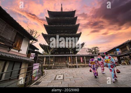 Drei Frauen mit Kimono laufen vor dem Kiyomizu-dera Tempel während eines atemberaubenden Sonnenuntergangs. Kyoto, Japan. Stockfoto