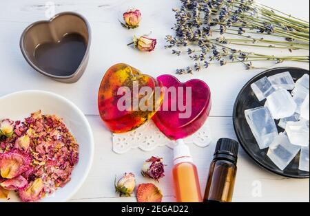 Herstellung handgemachte Seife mit kristallklarem Schmelz und gießen Seifenmischung. Bereit, rosa und gelb gebunden Seifen mit Rosenblättern und Lavendelblüten in verwenden Stockfoto