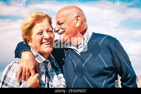 Glückliches Senior-Paar in der Liebe genießen Zeit zusammen - freudig Ältere Lebensstil und Ruhestand Konzept mit Mann flüsternd auf Frau Ohr Stockfoto